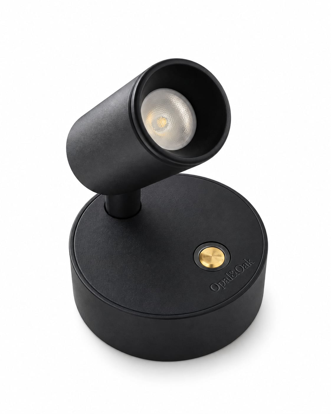 The black Opal&Oak rechargeable spotlight, angled so the lens, the brass switch on its base and the brand name printed beneath it are all in view